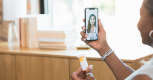 woman holding phone with a video call with a doctor and holding a pill bottle